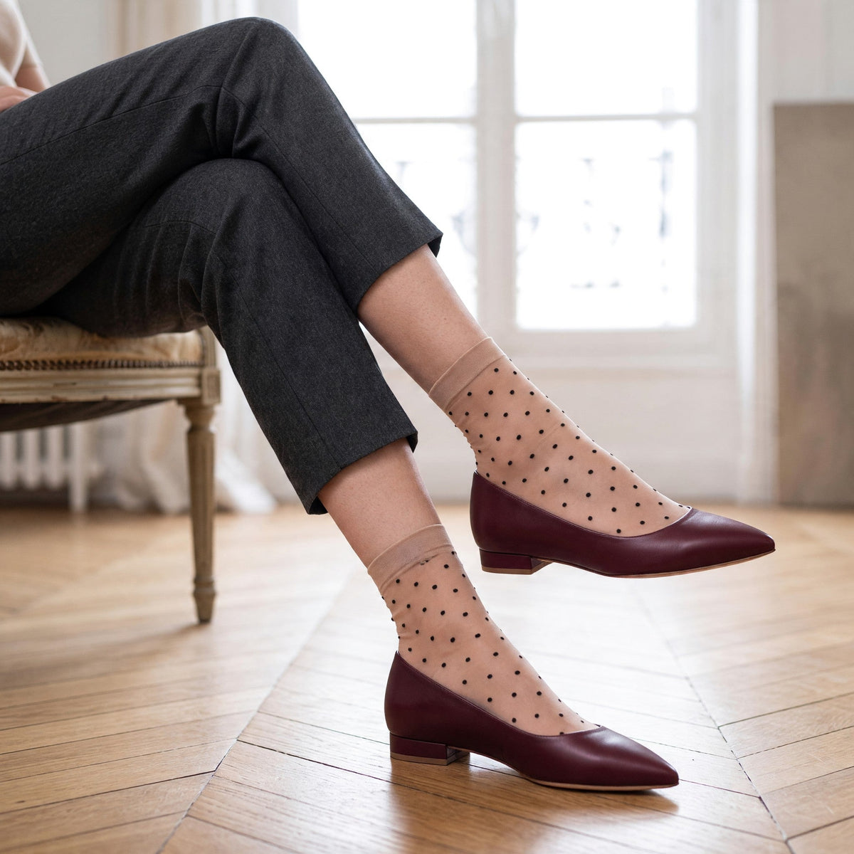 Ballerine a punta sfilata Riva Fiorita in nappa bordò indossate con calze velate a pois e pantalone grigio
