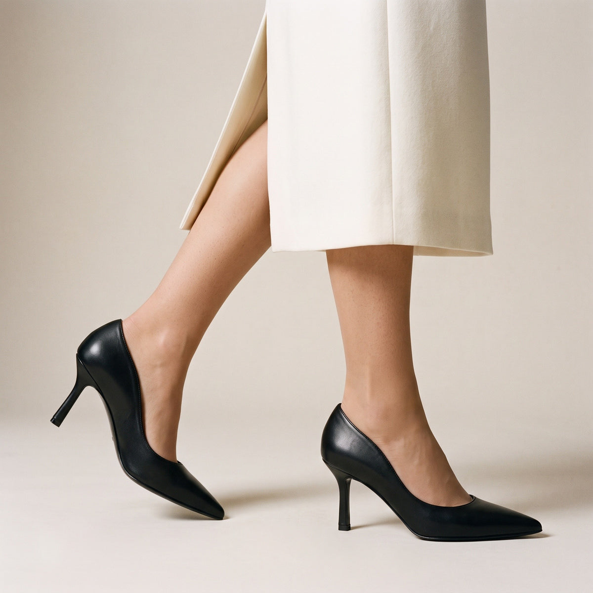 Décolleté Isabella Ferrante Partenope in nappa nera indossata con gonna midi avorio, stiletto da 75 mm e punta sfilata.